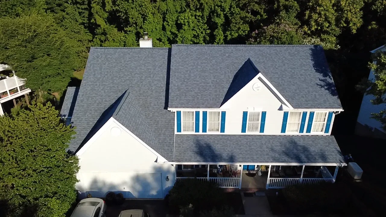 Aerial view of two-story home with new gray architectural shingle roof and white trim