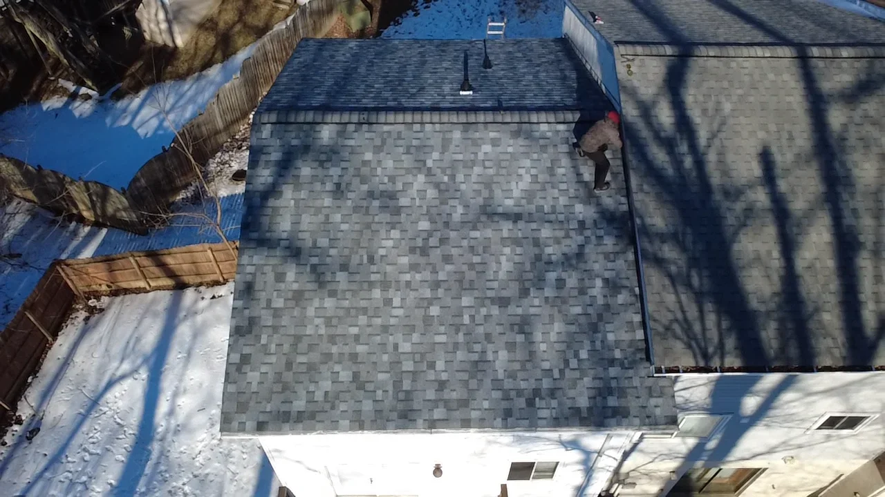Newly installed gray architectural shingles on residential roof with proper alignment and ridge cap details