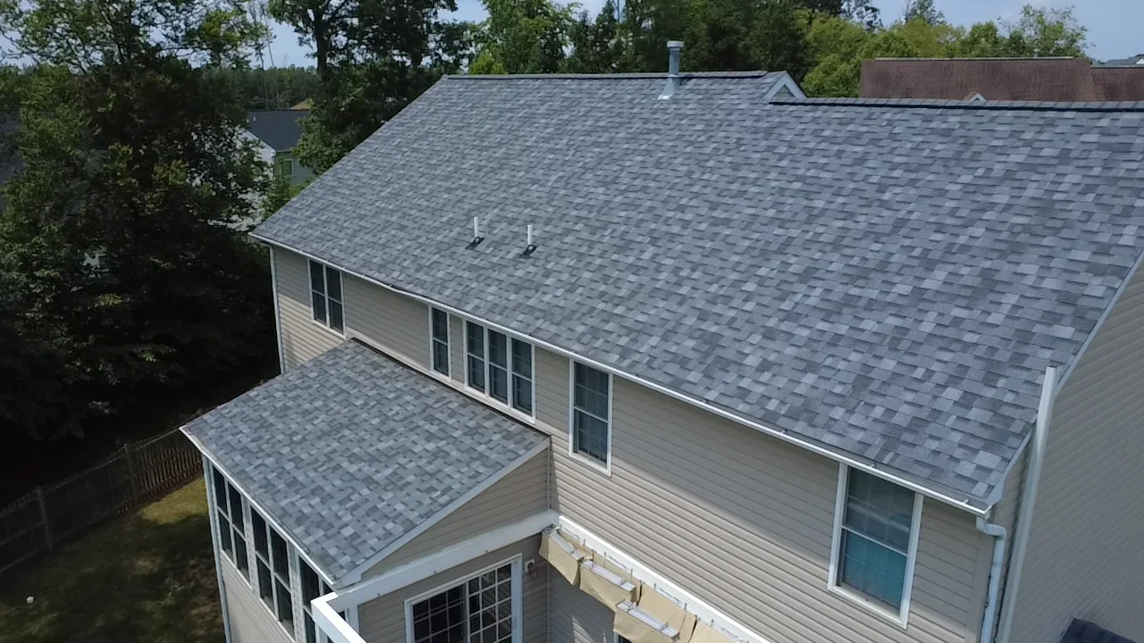 Gray architectural shingle roof on two-story home with white siding and multiple roof lines
