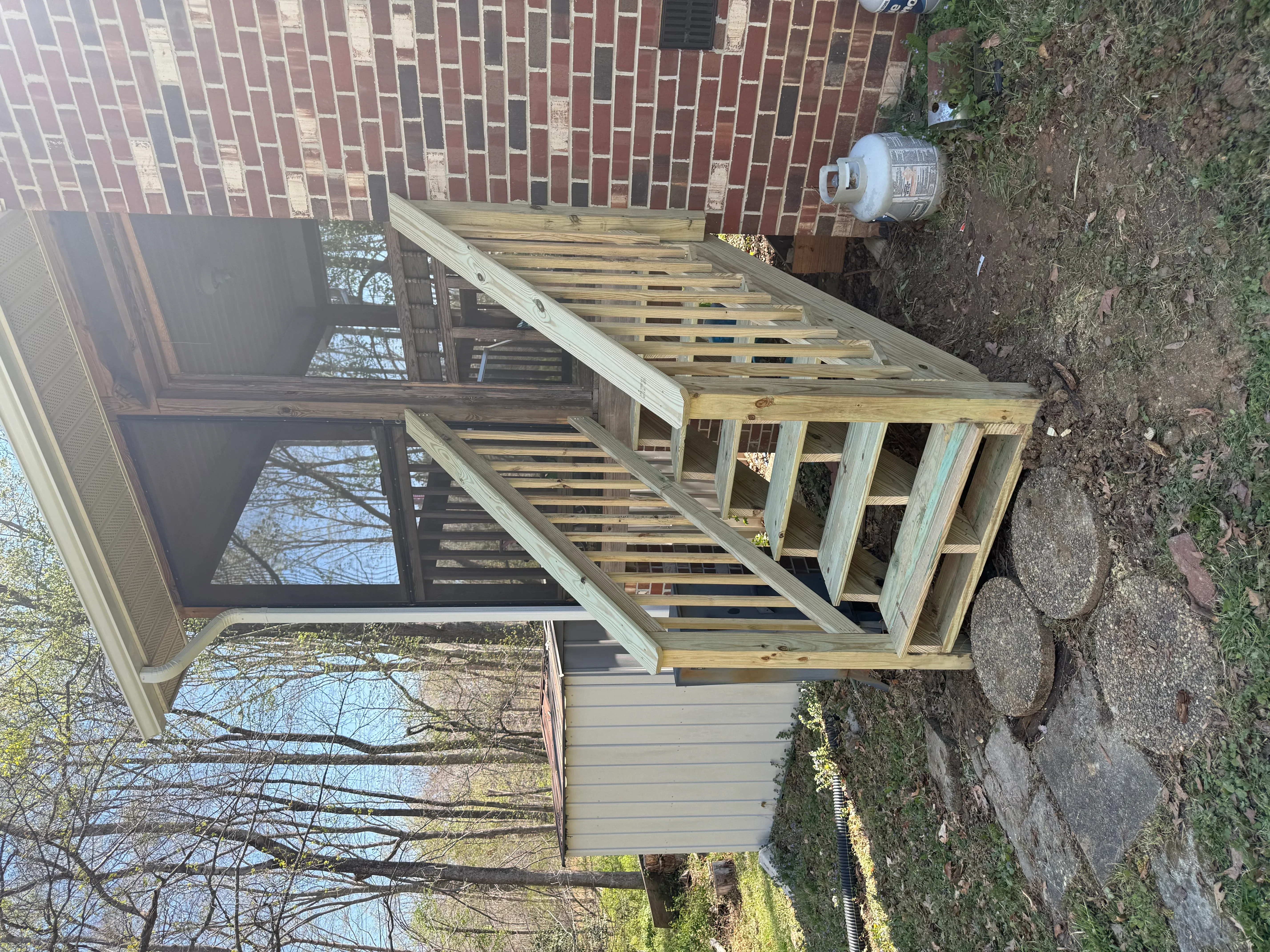 Pressure-treated wood deck with composite boards, support posts, and railing system under construction