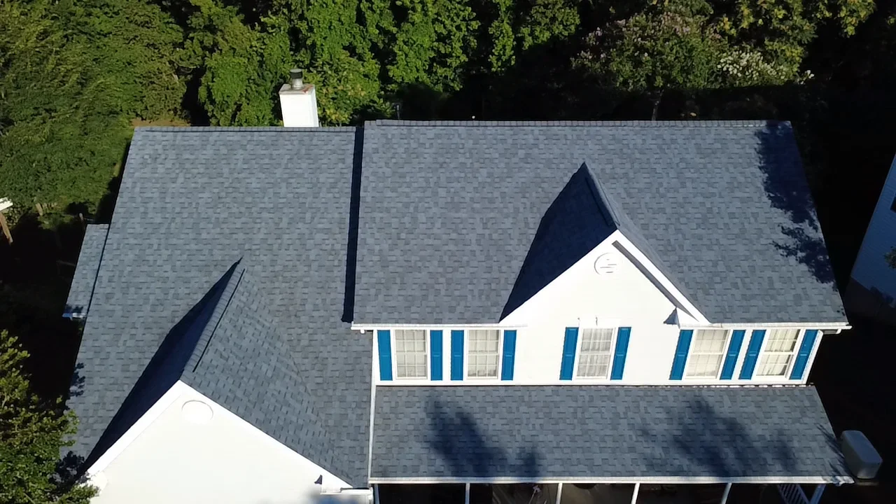 Gray architectural shingle roof with multiple gables and white chimney flashing