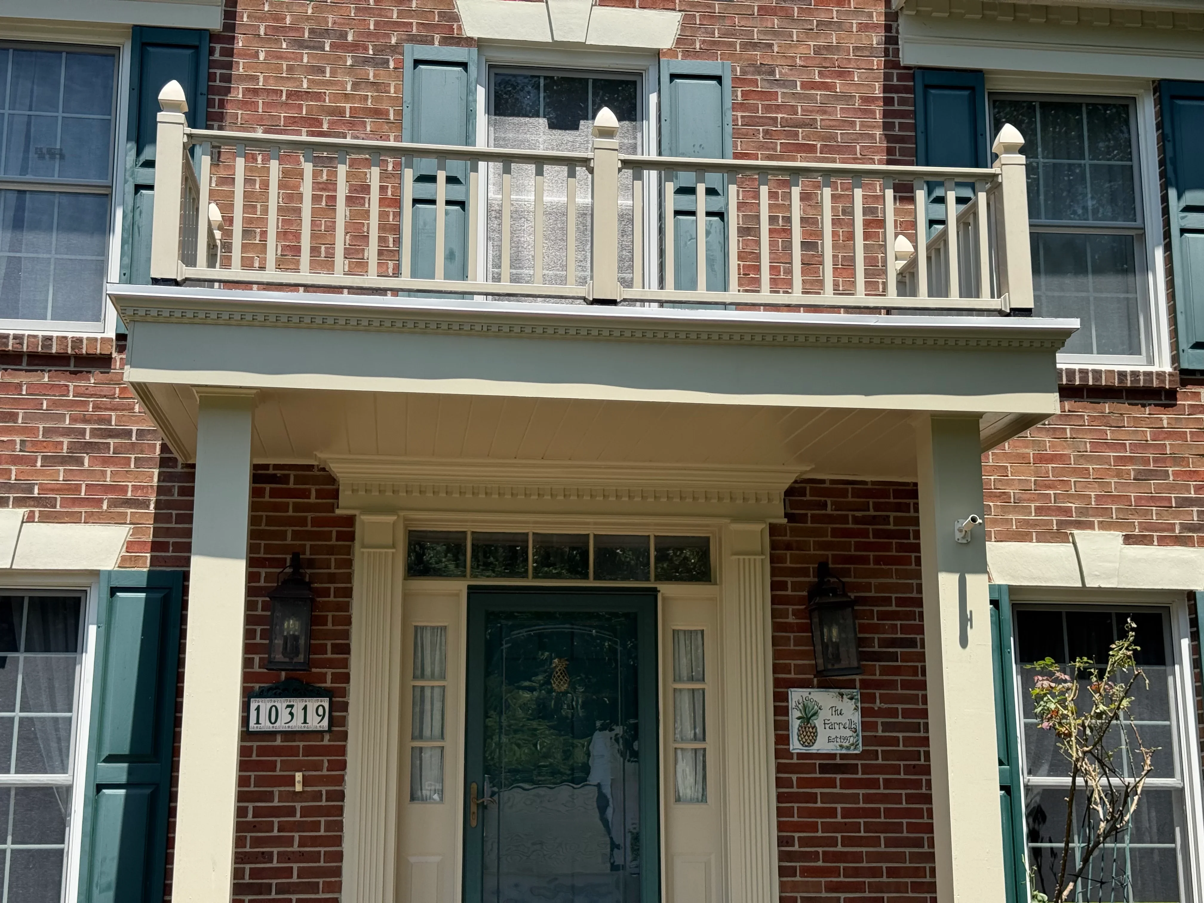 Cream aluminum soffit, fascia, and trim installed on red brick building facade with balcony railing