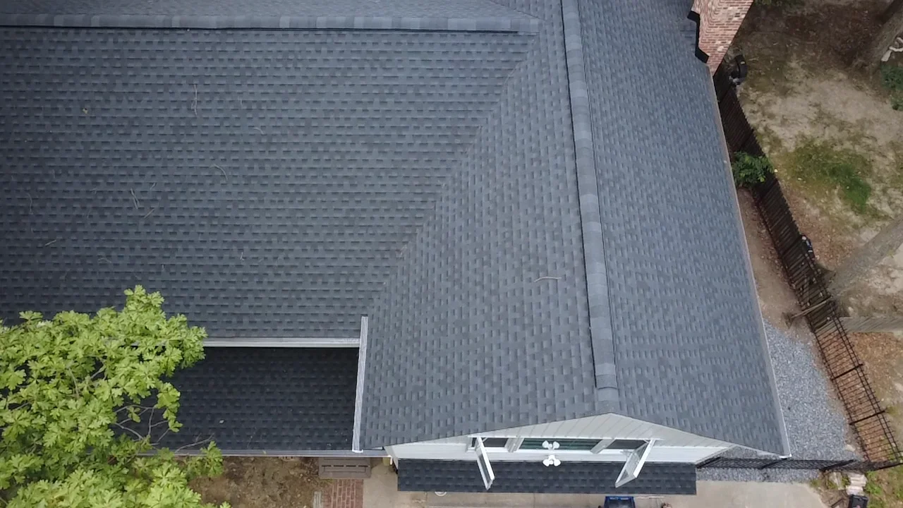 Charcoal gray architectural shingles installed on residential roof with new gutters