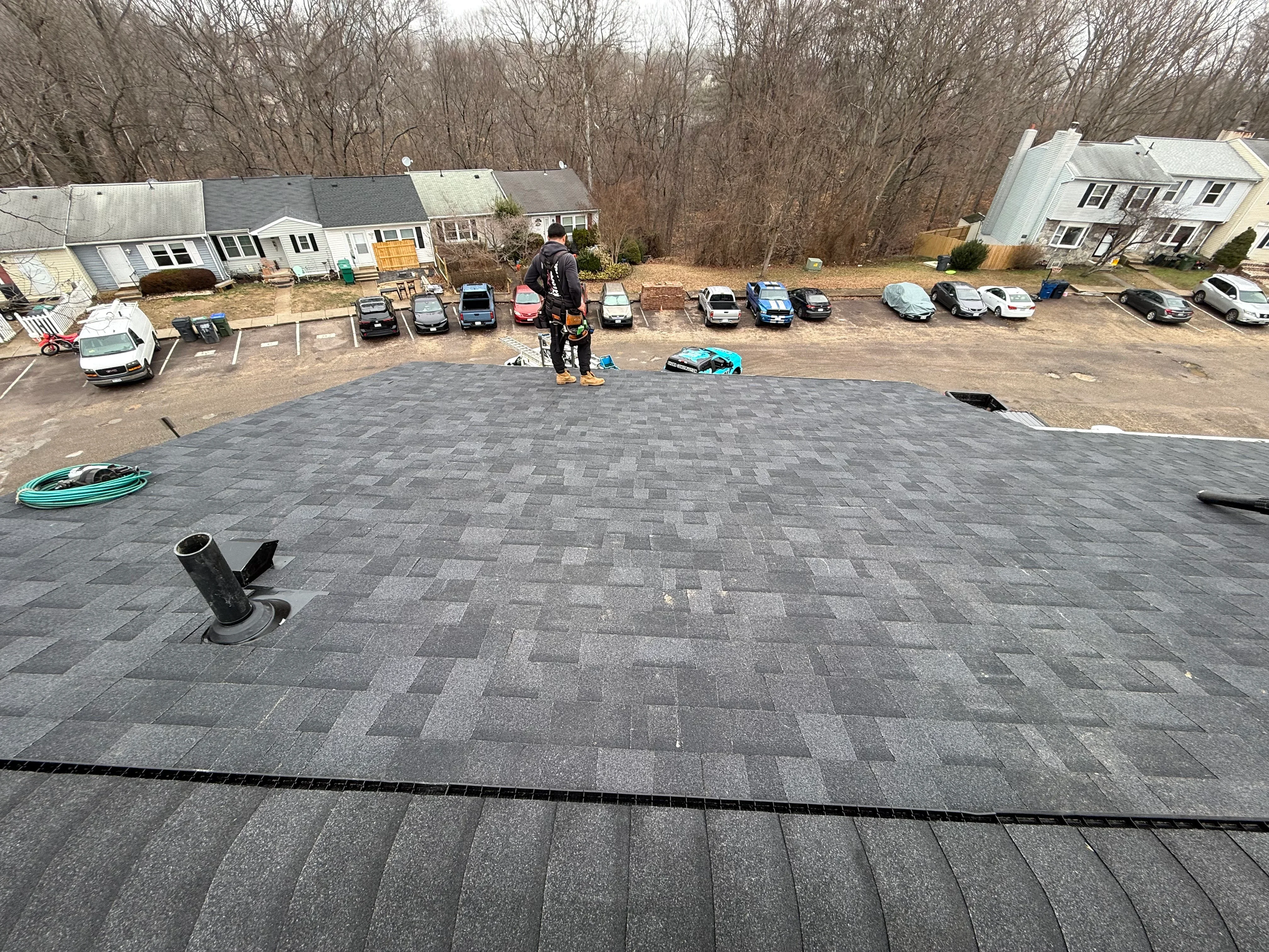Gray architectural shingles installed in staggered pattern with roof vent and edge trim