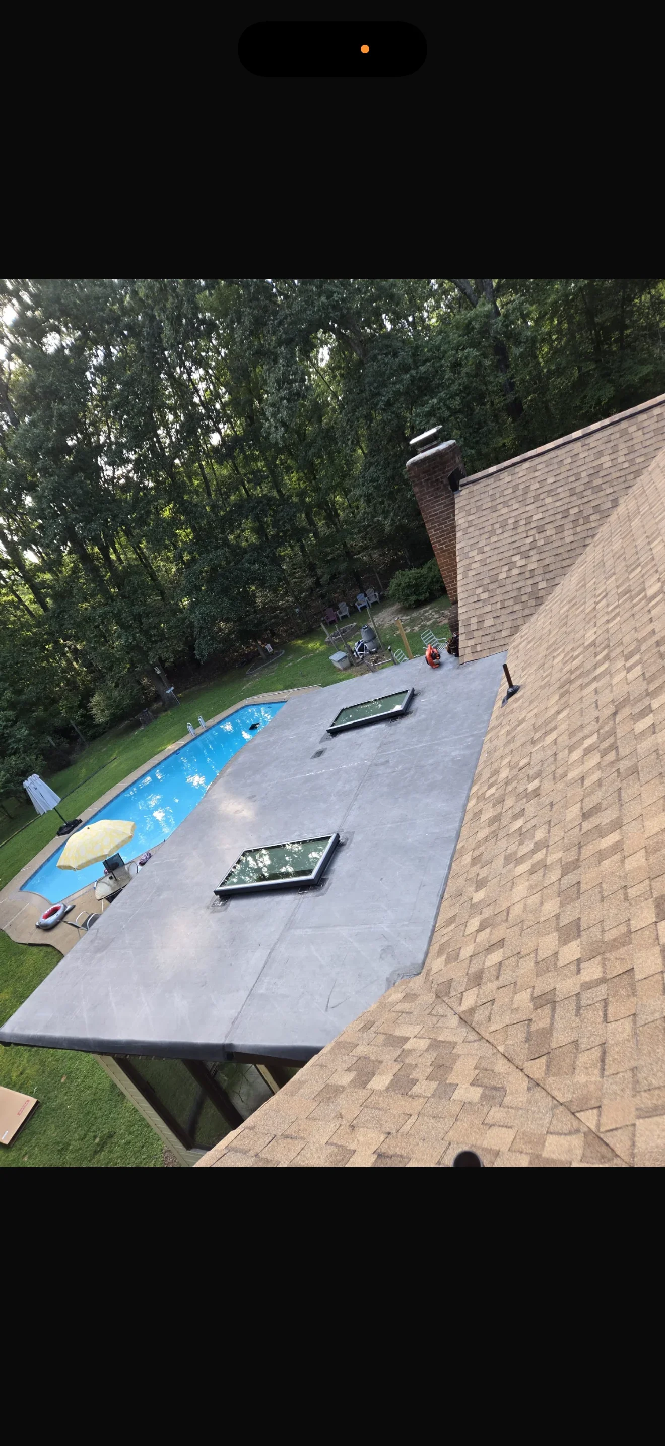 Flat roof with dark membrane and two skylight installations on brick home